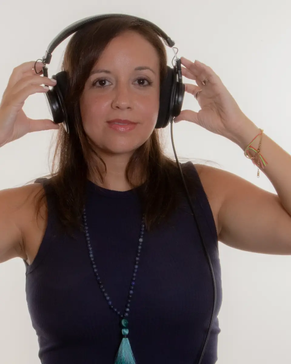 Majo Estevez sujetándose unos auriculares con ambas manos, retrato de estudio.